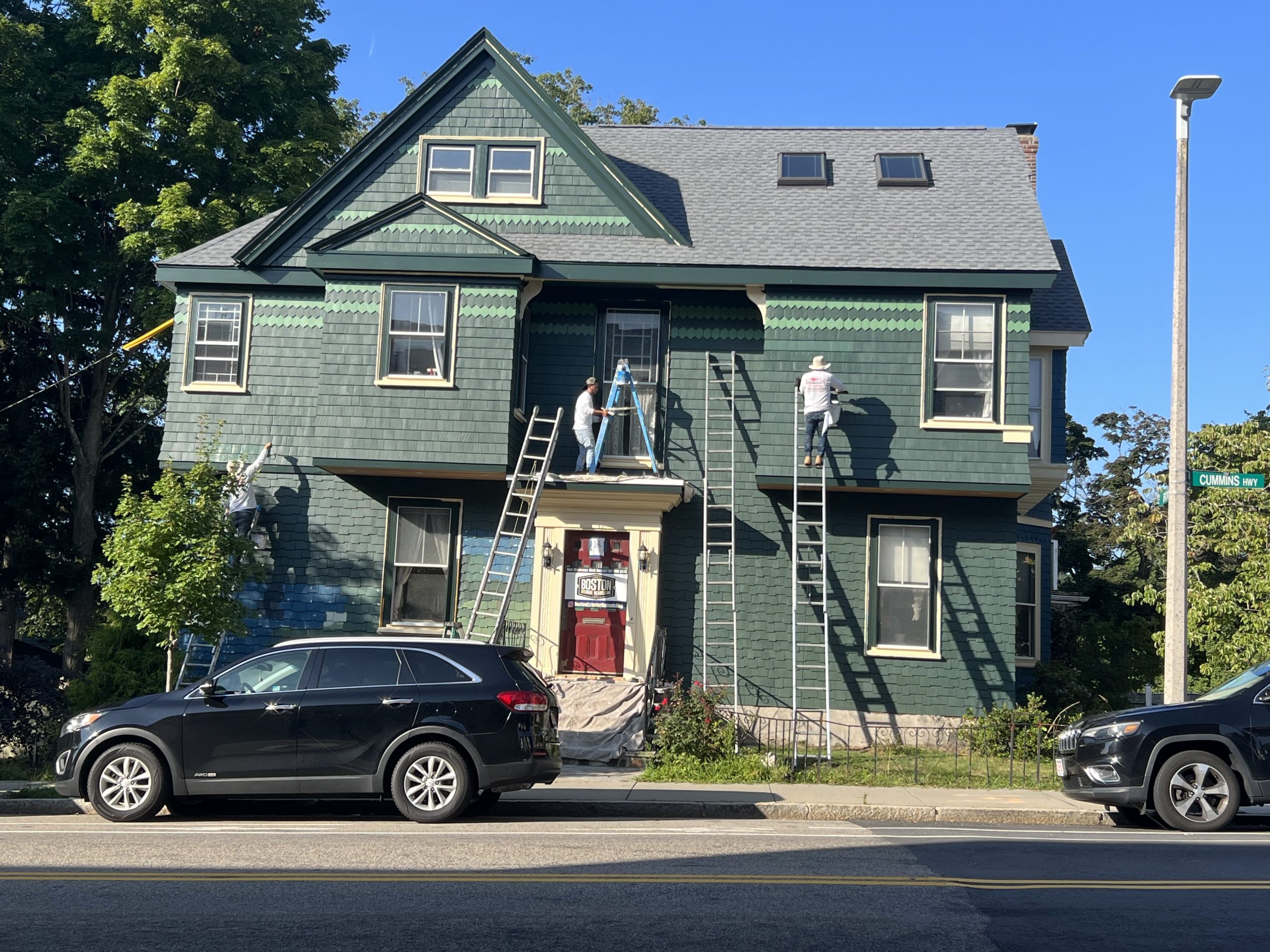 Professional painters working on a residential exterior painting project with ladders and exterior paint preparation
