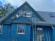 Professional exterior house painting services in progress on a historic blue home with decorative siding and detailed trim work.