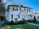 Professional exterior house painting on a colonial-style white home with black shutters and enhanced curb appeal.