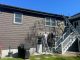 Professional painters scraping peeling paint from wood siding before exterior painting to ensure a durable finish.