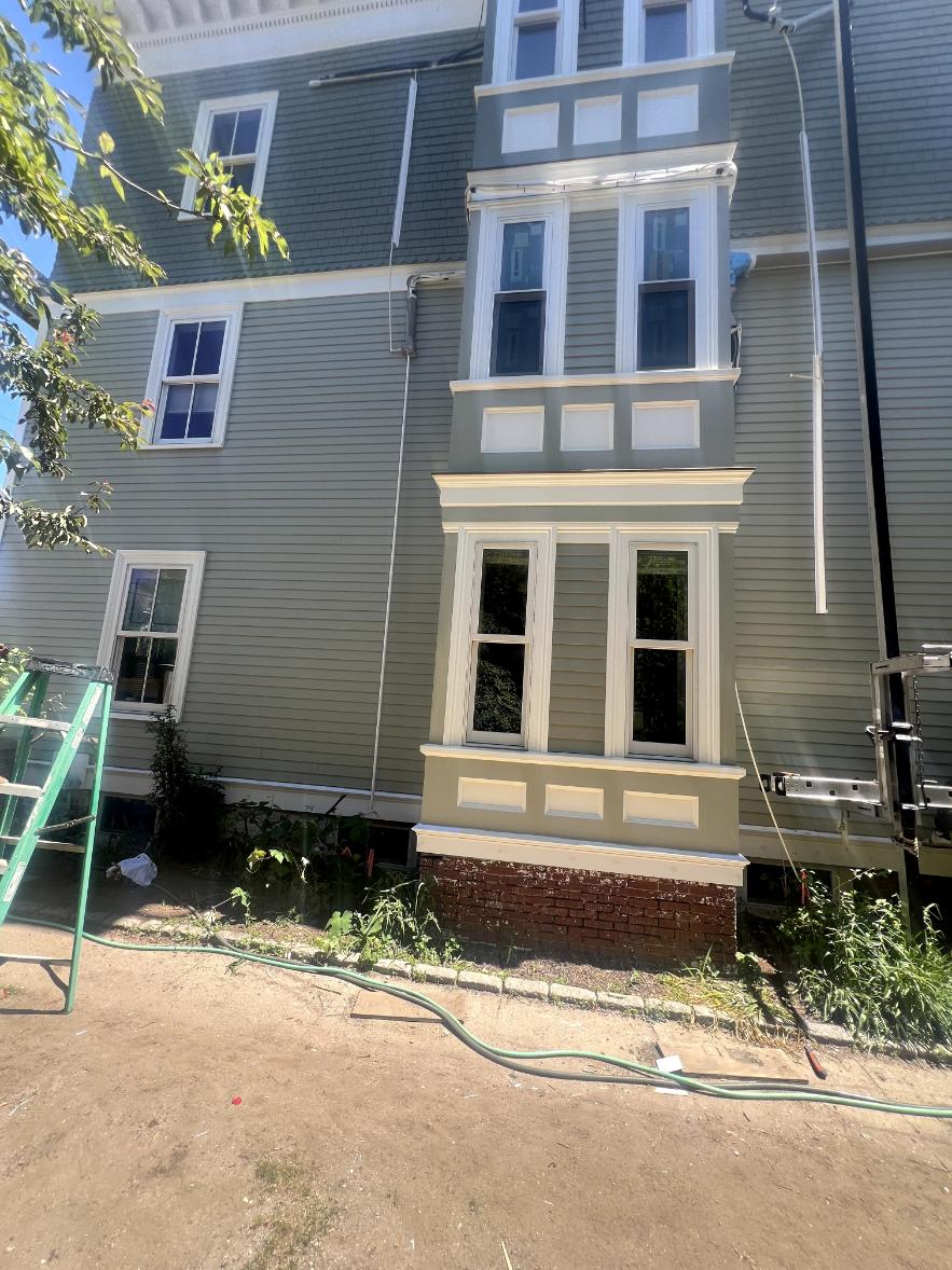 Exterior house painting of gray siding with white architectural window trim