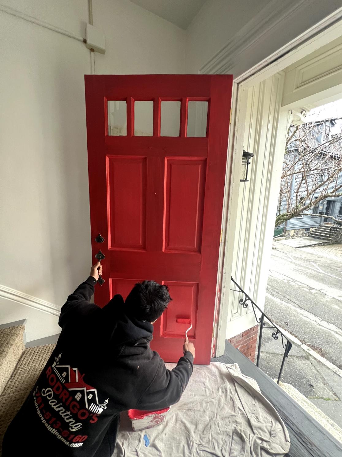 Front door painting in progress with a red finish on a traditional entryway