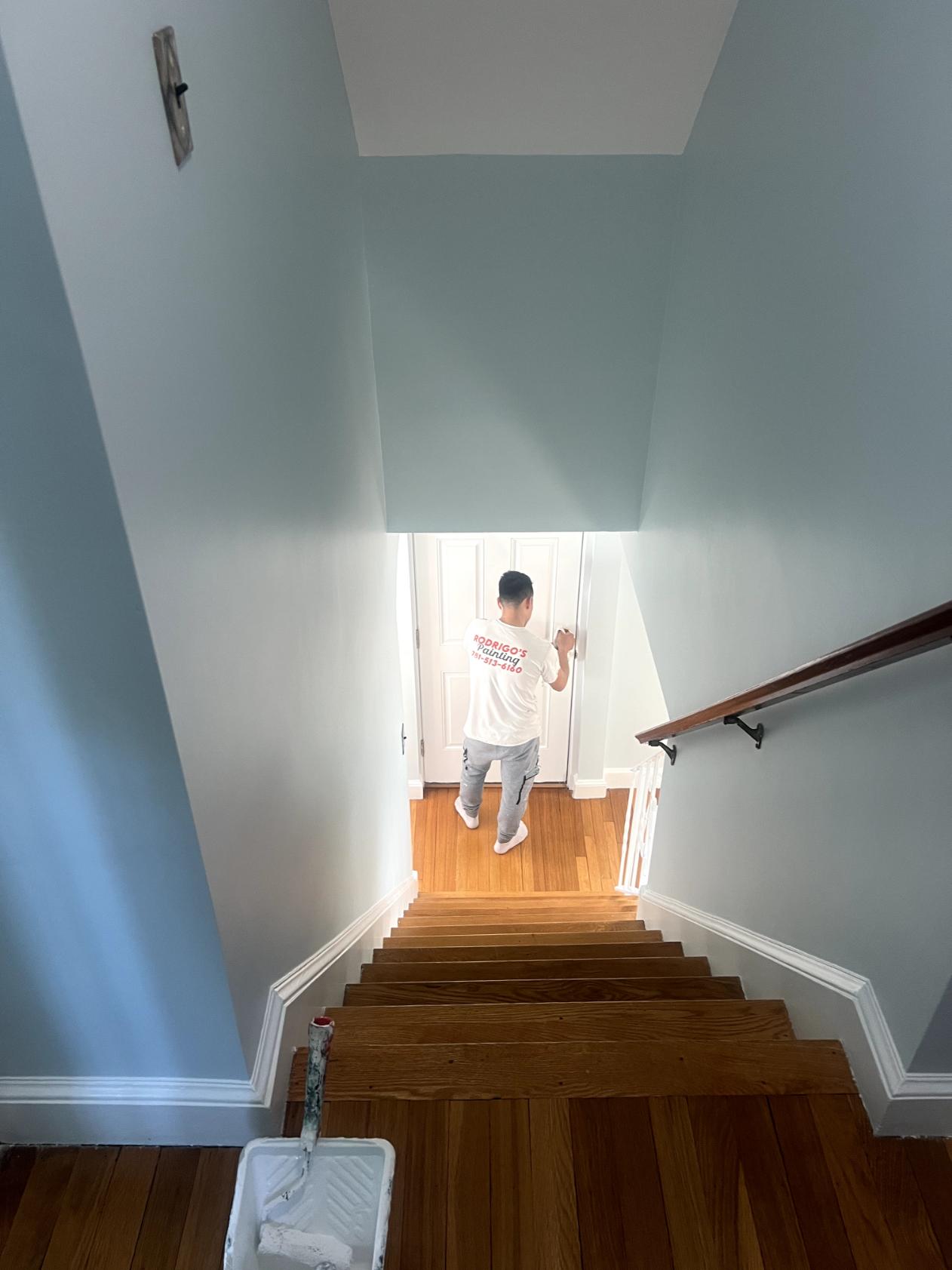 Professional stairway painting of light-colored walls, trim, and a white door in a residential home
